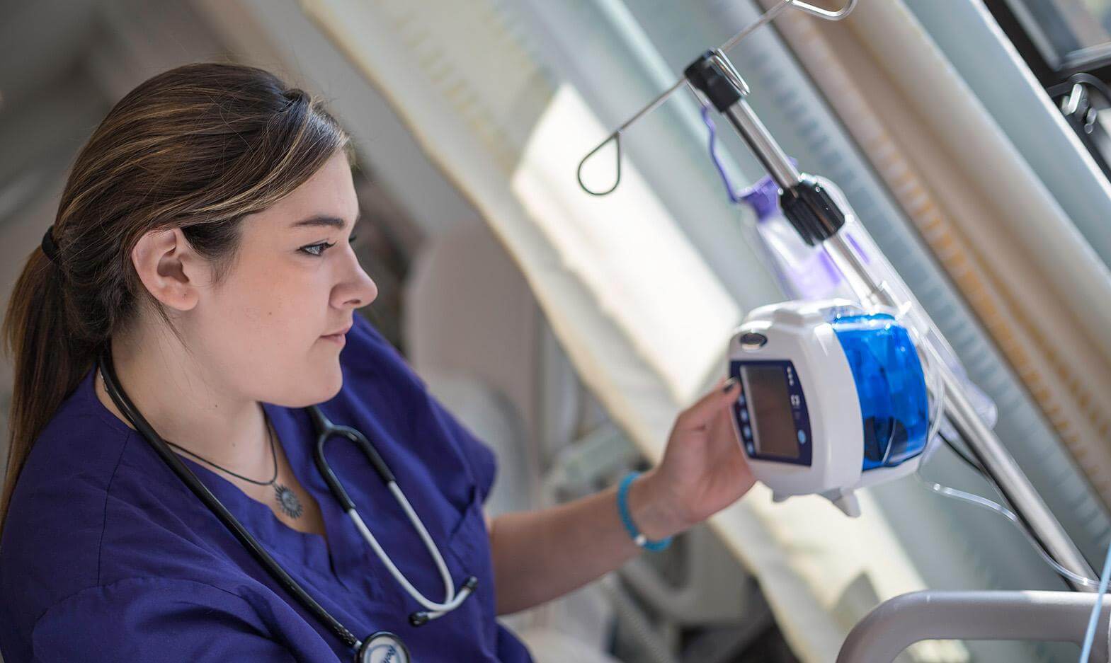 University of Bridgeport nursing student adjusting an IV pump in the simulation lab