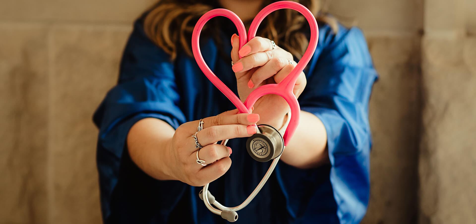 A nursing student holding a stethoscope shaped into a heart